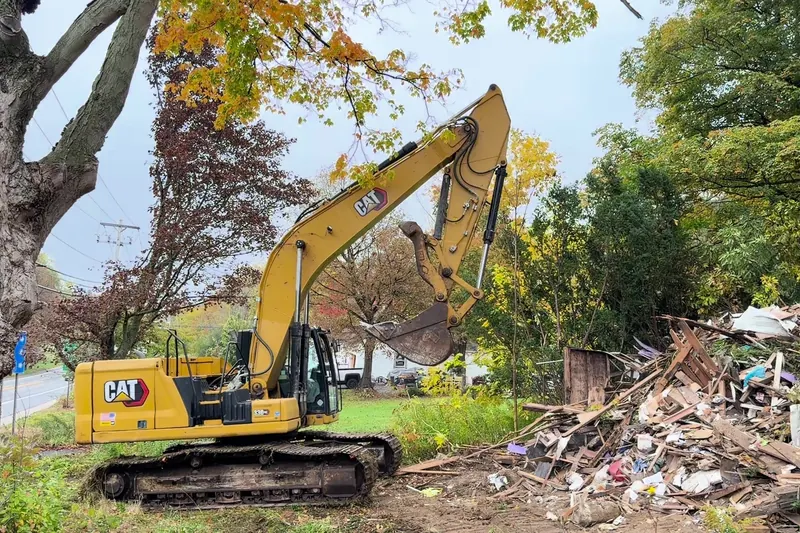 CAT excavator working the debris pile after a house teardown