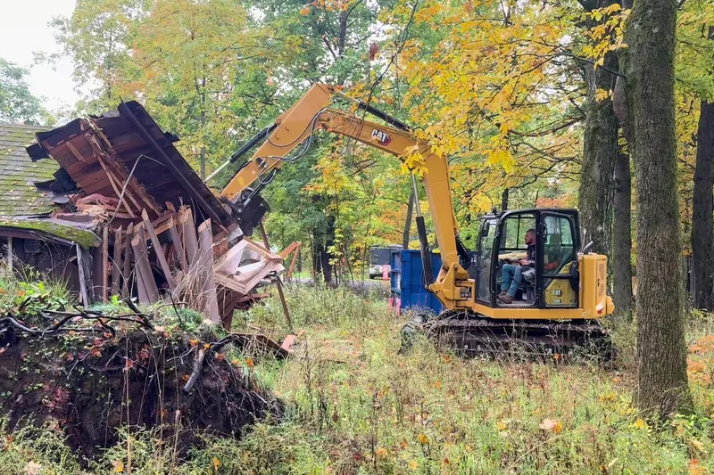 Backwell excavator pulling the roof off a house during a teardown