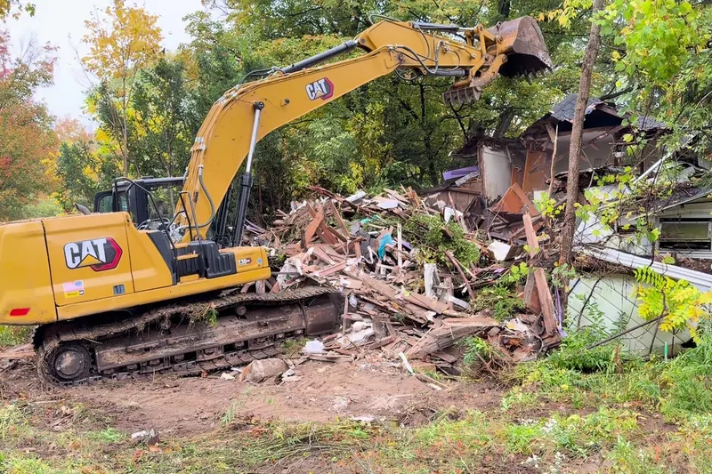 Excavator loading house demolition debris for hauling